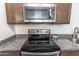 Close-up of stainless steel microwave and electric cooktop, complemented by granite countertops at 8924 N 102Nd Ln, Peoria, AZ 85345