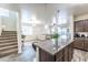 View of kitchen island and living space. Staircase with carpeted steps to the left at 8924 N 102Nd Ln, Peoria, AZ 85345
