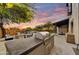Spacious outdoor kitchen with built-in grill, prep area, and fire pit, perfect for backyard gatherings with sunset views at 9669 E Chino Dr, Scottsdale, AZ 85255