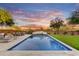 Inviting pool with sleek stone accents, lush landscaping, and relaxing lounge chairs under a beautiful Arizona sunset at 9669 E Chino Dr, Scottsdale, AZ 85255