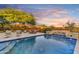 Sparkling pool boasts stone details, desert views, cascading waterfall, and comfortable lounge seating for sunset enjoyment at 9669 E Chino Dr, Scottsdale, AZ 85255