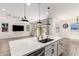 Modern kitchen island with stainless steel sink, white cabinets and three pendant lights at 9837 E Satellite Dr, Mesa, AZ 85212