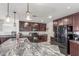 Beautiful kitchen featuring granite countertops, dark wood cabinets, stainless steel appliances, and modern lighting at 12128 W Range Mule Dr, Peoria, AZ 85383