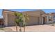 Close-up of a tan single-story house featuring a three-car garage, tiled roof, and low-maintenance desert landscaping at 12389 W Marguerite Ave, Avondale, AZ 85323