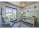 Charming Bedroom featuring a gray armchair, crib, and a large window with natural light at 1320 N Brittany Ln, Gilbert, AZ 85233