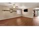 Neutral living room with wood floors, ceiling fan, TV, shelving and view into the kitchen at 13722 N 150Th Ln, Surprise, AZ 85379