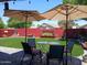 Inviting backyard featuring artificial grass, seating under umbrellas, a red brick wall, and well-kept landscaping at 14211 N 149Th Dr, Surprise, AZ 85379