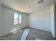 A bright bedroom with a neutral color palette, carpet floors and a view through the window at 15785 W Beryl Ave, Waddell, AZ 85355