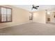Bright, large bedroom with neutral carpeting, ceiling fan and a view of the entrance to the en suite bathroom at 1623 E Leaf Rd, San Tan Valley, AZ 85140