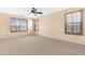 Spacious bedroom featuring neutral carpeting, light beige walls and two windows with wooden shutter-style blinds at 1623 E Leaf Rd, San Tan Valley, AZ 85140