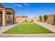 Backyard features faux grass patches, mature landscaping, and a covered patio at 1762 E Elegante Dr, Casa Grande, AZ 85122