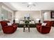 Cozy living room featuring two red chairs, a green sofa, a ceiling fan and ample natural light at 2507 E Eleana Ln, Gilbert, AZ 85298