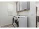 Bright laundry room with white washer and dryer, overhead storage, and a window to bring in natural light at 300 N Gila Springs Blvd # 181, Chandler, AZ 85226