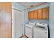A modern laundry room equipped with a front-loading washer, dryer, and ample cabinet space above for storage at 3138 W Danbury Dr, Phoenix, AZ 85053