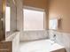 A bright bathroom features a luxurious, standalone tub with marble surround and window at 4020 W Menadota Dr, Glendale, AZ 85308