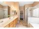 Bright main bathroom featuring double sinks and a tiled shower, complemented by a bathtub for a spa-like experience at 4020 W Menadota Dr, Glendale, AZ 85308