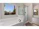 Bright bathroom featuring a soaking tub, glass-enclosed shower, and a large picture window at 4526 E Bannock St, Phoenix, AZ 85044