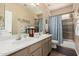 Well-lit bathroom featuring a double sink vanity, a decorative mirror, and a shower-tub combo at 5993 W Topeka Dr, Glendale, AZ 85308