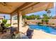 Relaxing covered patio overlooking the sparkling pool, lush greenery, and blue skies at 5993 W Topeka Dr, Glendale, AZ 85308
