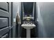 Stylish powder room with a unique pedestal sink, decorative mirror, and modern dark blue wall paint at 6338 W Raymond St, Phoenix, AZ 85043
