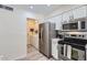 Contemporary kitchen features stainless steel appliances, and gray vinyl flooring, with access to laundry area at 828 E Le Marche Ave, Phoenix, AZ 85022