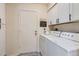 Cozy laundry room with white cabinets and appliances plus decorative quote that says, 