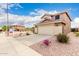 Desert-landscaped front yard of a tan two-story house, complete with a driveway and two-car garage at 864 S 223Rd Ln, Buckeye, AZ 85326