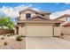 Well-kept two-story home showcasing a tan stucco exterior, tidy landscaping, and a spacious two-car garage at 864 S 223Rd Ln, Buckeye, AZ 85326