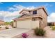 Exterior shot of a two-story tan home, featuring desert landscaping in the front and a two-car garage at 864 S 223Rd Ln, Buckeye, AZ 85326