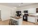 Kitchen with white cabinets, black appliances, and an island with seating, providing a modern cooking space at 871 E Melanie St, San Tan Valley, AZ 85140