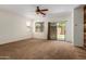 Spacious carpeted living room with a ceiling fan and backyard access through sliding glass doors at 871 E Melanie St, San Tan Valley, AZ 85140