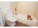 Bright bathroom featuring a toilet, tub/shower combo, and tiled walls at 925 E Wagoner Rd, Phoenix, AZ 85022