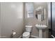 Well-lit half bathroom featuring a pedestal sink, toilet, and modern fixtures at 10071 W Angels Ln, Peoria, AZ 85383