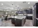 This spacious kitchen features dark cabinets, stainless appliances, a granite island, and modern lighting at 10071 W Angels Ln, Peoria, AZ 85383