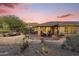 Beautiful desert home backyard with a covered patio, seating area, and lush desert landscaping at 11400 E Helm Dr, Scottsdale, AZ 85255