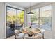Bright dining area features a round table, stylish pendant lighting, and a sliding door to the outdoor patio at 11400 E Helm Dr, Scottsdale, AZ 85255