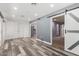 Open living area with wood floors, gray accent wall, and barn door entryway to another room at 14224 N Newcastle Dr, Sun City, AZ 85351