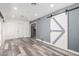 Bright living room with wood flooring, gray accent wall, and a modern sliding barn door at 14224 N Newcastle Dr, Sun City, AZ 85351