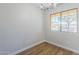 An empty dining room features wood flooring, a modern light fixture, and a view from the window at 16159 W Maui Ln, Surprise, AZ 85379