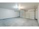 The garage has a smooth concrete floor, a bright overhead light, and a white paneled garage door at 16159 W Maui Ln, Surprise, AZ 85379