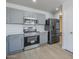 Updated kitchen showcasing gray cabinets, quartz countertops, stainless steel appliances, and durable wood-look flooring at 16159 W Maui Ln, Surprise, AZ 85379