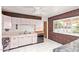 Retro kitchen featuring pastel pink cabinets, marbled countertops, brick wall accent, and large window at 1810 N 74Th St, Scottsdale, AZ 85257