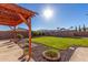 Well-maintained backyard with a grassy lawn, mature plants, and a charming pergola perfect for outdoor relaxation at 18581 W College Dr, Goodyear, AZ 85395