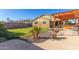 Beautiful backyard featuring a well-manicured lawn, mature plants, a covered patio, and a charming pergola at 18581 W College Dr, Goodyear, AZ 85395