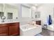 Primary bathroom featuring a soaking tub, dual sinks, and plenty of natural light at 18581 W College Dr, Goodyear, AZ 85395