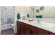 Bright bathroom featuring a double vanity with dark cabinets, a large mirror, and a tub at 18581 W College Dr, Goodyear, AZ 85395