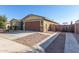 Side view of the single-story home with a two-car garage and gated side yard at 18581 W College Dr, Goodyear, AZ 85395