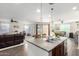 Kitchen island with a sink and granite countertop overlooks a dining and living area at 18581 W College Dr, Goodyear, AZ 85395