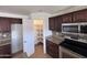 Kitchen with stainless steel appliances, granite countertops, dark wood cabinetry, and a pantry with shelving at 18629 W Fulton St, Goodyear, AZ 85338