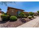 Well-manicured landscaping accentuates this tan home with blue shutters, creating a charming curb appeal on a sunny day at 20283 N 273Rd Ave, Buckeye, AZ 85396